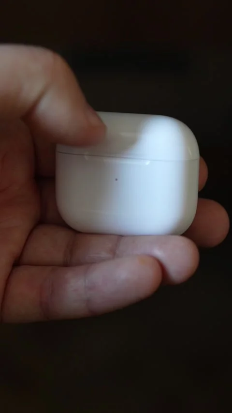 A man holding a pair of wireless earbuds in an open charging case Stock Footage 327950580