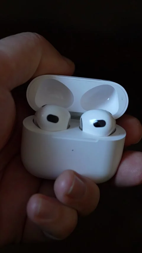 A man holding a pair of wireless earbuds in an open charging case Stock Footage 327951783