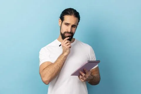 Man holding paper notebook, having thoughtful facial expression, planning. Stock-Fotos