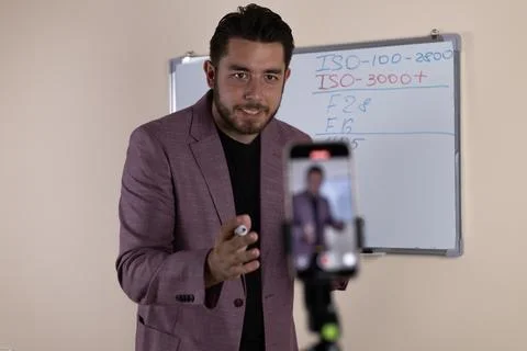 A man is holding a phone to record himself while pointing at the camera Foto stock