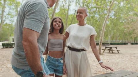 Man holding phone while sitting on park bench happy to greet his family Stock Footage 255962397