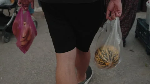 A man holding a plastic bag with melon in the street. Stock Footage 230606173