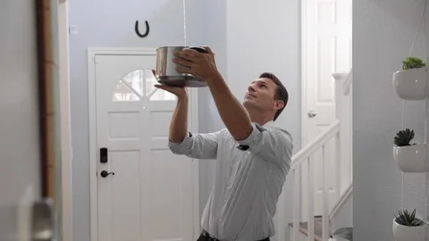 Man holding a pot where water flows from the ceiling Stock Footage 120893322