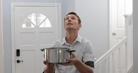 Man holding a pot where water flows from the ceiling Stock Footage 120893387
