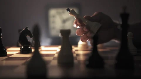 A man is holding a queen piece in his hand, contemplating his next moves Stock Footage 312821741