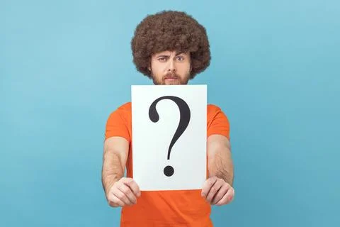 Man holding question mark, finding smart solution, asking for advice, looking at Foto stock