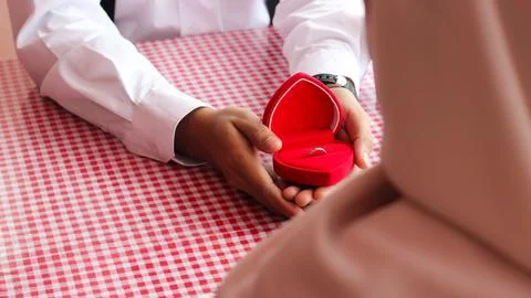 The man holding the red box in the shape of love is proposing to his girlfr.. Stock Photos