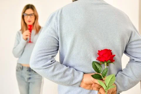 A man holding a red rose behind his back . Foto stock