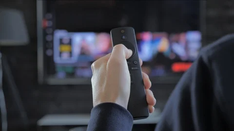 Man holding a remote control and searching for streaming media to play Video stock 103473043