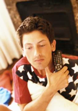 Man holding remote control in hand and pillow under arm Stock Photos
