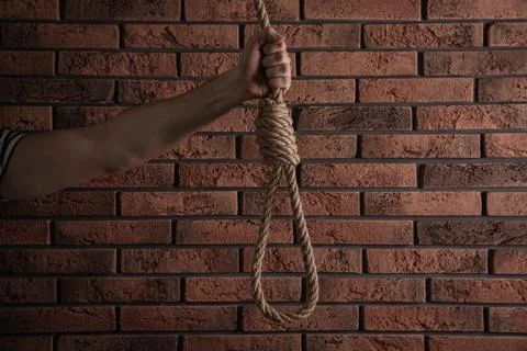 Man holding rope noose near brick wall, closeup Stock Photos