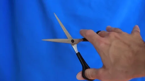 Man holding scissors in his hand on the blue background 스톡 동영상 70751169