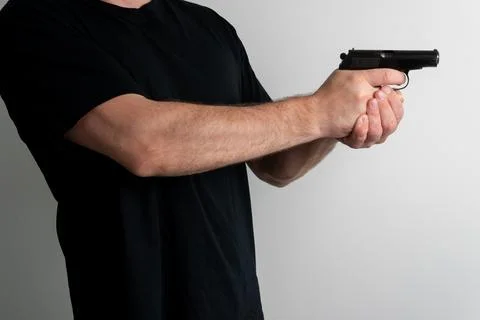 Man holding semi automatic pistol in shooting stance against plain background Fotos Stock