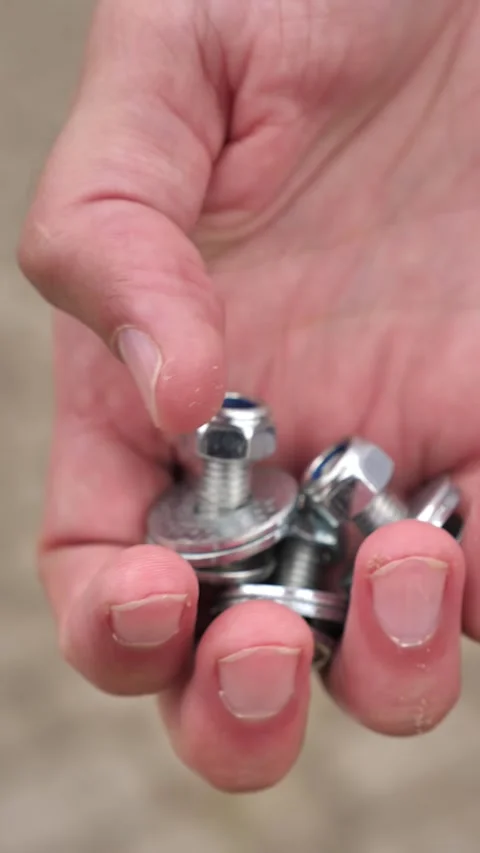 Man holding silver screws and washers close-up, small parts in hands vertical Stock Footage 252138850