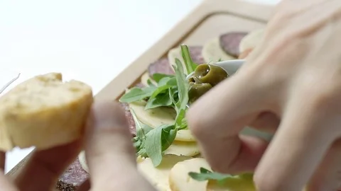 Man holding slice of bread and takes some cheese and ham from the wooden board,  스톡 동영상 83655015