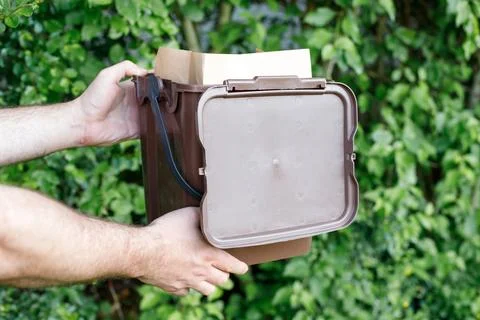 Man holding a small kitchen compost bin with a paper bag for organic bio-wa.. Stock Photos