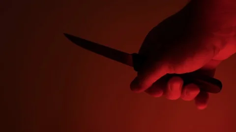 Man holding small knife in hand at night, backlit with red light. Slow motion. Stock Footage 116409886