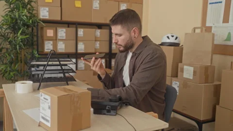 Man holding smartphone and checking parcel at a shipping desk inside a buil.. Stock Footage 337362860