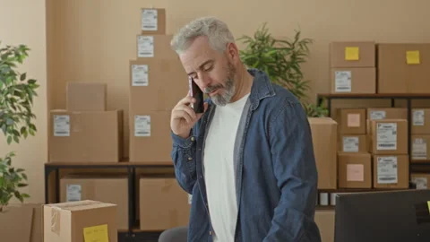Man holding smartphone and papers while reading package details in a buildi.. Stock Footage 337437091