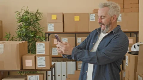 Man holding smartphone and tapping screen amid stacked parcels and shipping.. Stock Footage 337437322