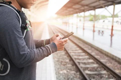 Man holding smartphone with backpack at train station Stock Photos