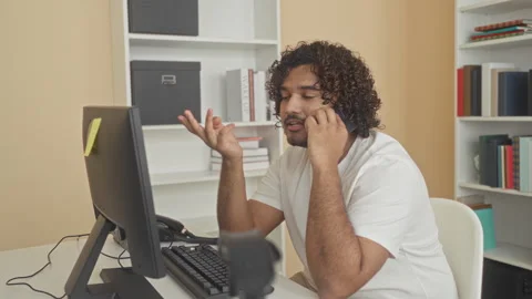 Man holding smartphone to ear and gesturing with hand at a desk inside a bu.. 動画素材 337395655