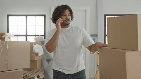 Man holding smartphone to ear and resting hand on cardboard boxes inside bu.. Stock Footage 337404616