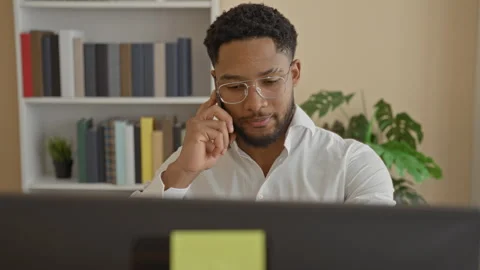 Man holding smartphone to ear while looking at computer monitor in building.. Stock Footage 337439877
