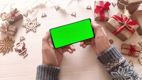 Man holding smartphone with green screen on Christmas background with gifts. Stock Footage 165394428