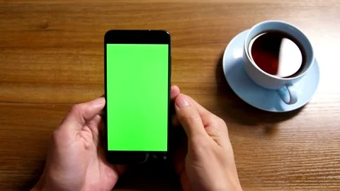 Man holding smartphone with green screen at cafe table Stock Footage 334108399