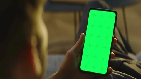 Man holding a smartphone with green screen at home Stock Footage 334137072
