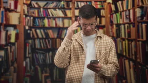 Man holding smartphone, hand on head and frowning while scanning messages i.. Stock Footage 339197165