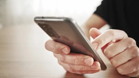 A man is holding a smartphone in his hands and using or surfing the Internet Stock Footage 253595448