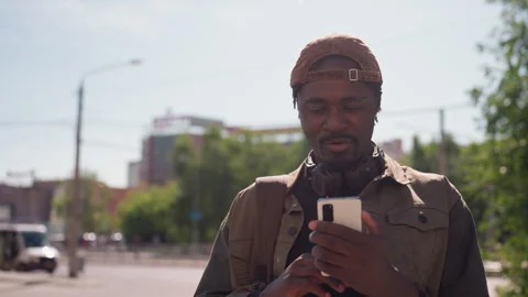 Man holding smartphone looking at device in urban outdoor street scene featuring Stock Footage 345125987