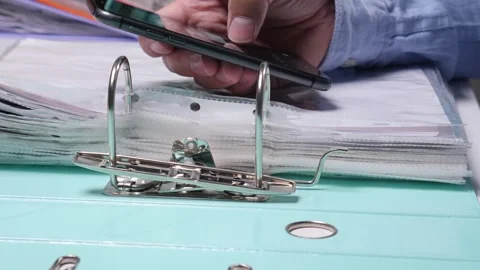 Man holding a smartphone over an open ring binder, scanning or documenting Stock Footage 342763140