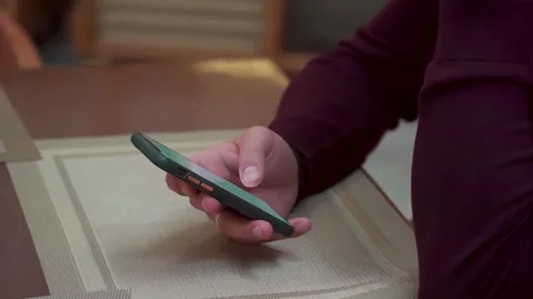 Man holding smartphone at a table, close-up, everyday life scene Stock-Footage 294627835