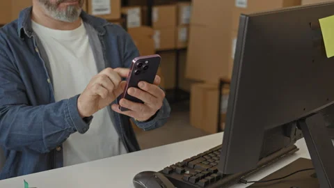 Man holding smartphone taps screen while checking parcel boxes at a packing.. Stock Footage 347860778