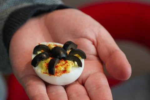 Man holding Spider Deviled Egg in Hand. Healthy Halloween Snack 写真素材
