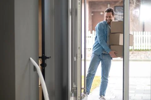 Man holding stack of boxes entering house Stock Photos