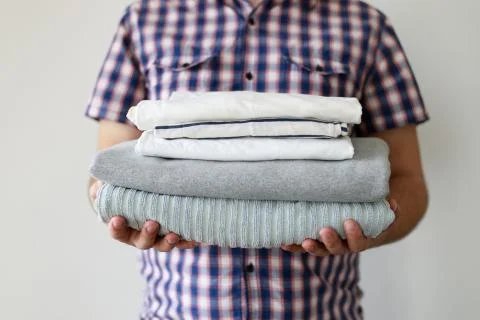 Man holding stack of clean laundered clothes Stock Photos