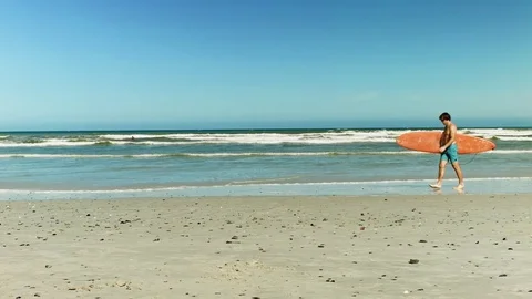 Man holding surfboard at beach Stock Footage 76521250