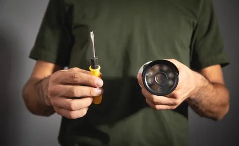 Man holding surveillance security camera and screwdriver. Stock Photos