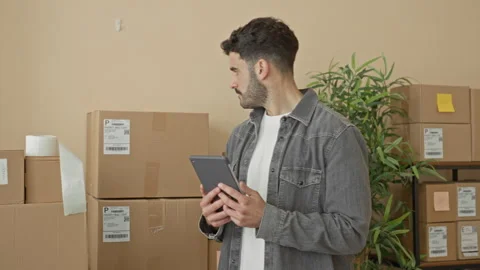 Man holding tablet and checking cardboard packages and shipping labels in a.. Video stock 337373337