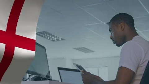 Man holding tablet and comparing monitors in tech office, red-cross flag waving, Stock Footage 334351735