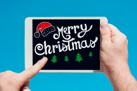 Man holding a tablet device  with text "Merry Christmas" and touching the scr Stock Photos