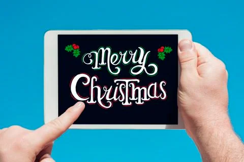 Man holding a tablet device  with text "Merry Christmas" and touching the scr Stock Photos