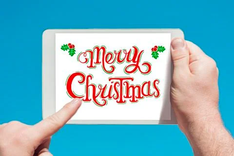 Man holding a tablet device  with text "Merry Christmas" and touching the scr Stock Photos