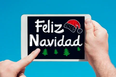 Man holding a tablet device with text in Spanish "Feliz Navidad (Merry Christ Stock Photos