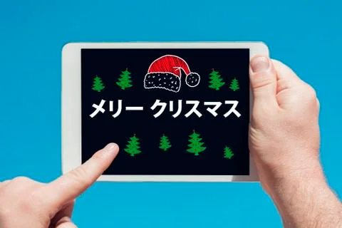 Man holding a tablet device with text in japanese "Merry Christmas" and touch Stock Photos