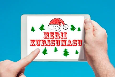 Man holding a tablet device with text in japanese "Merii Kurisumasu" (Merry C Stock Photos